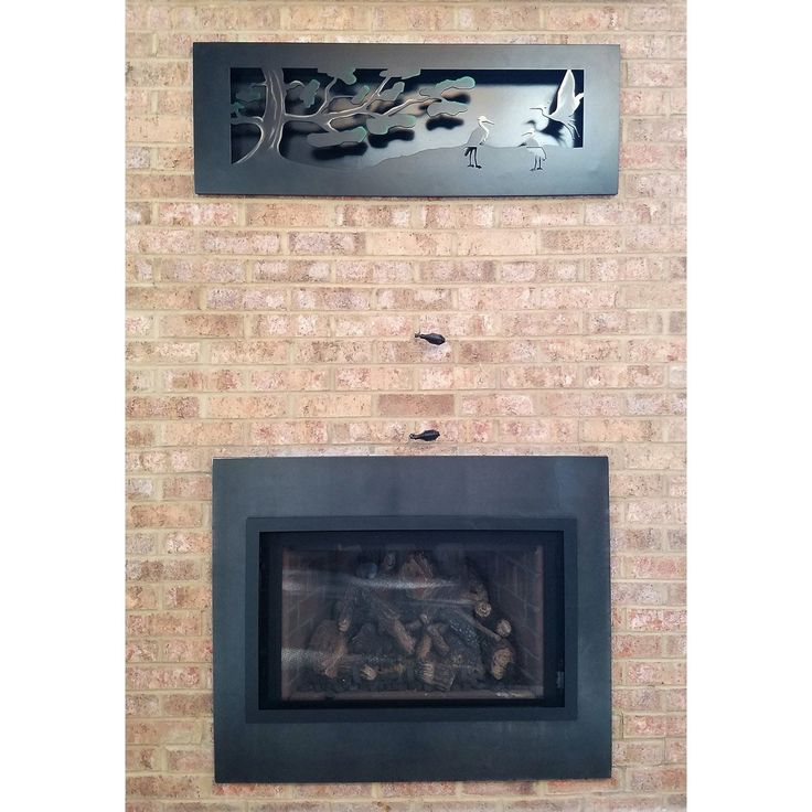 a brick fireplace with a metal sign above it and two birds flying over the fire place