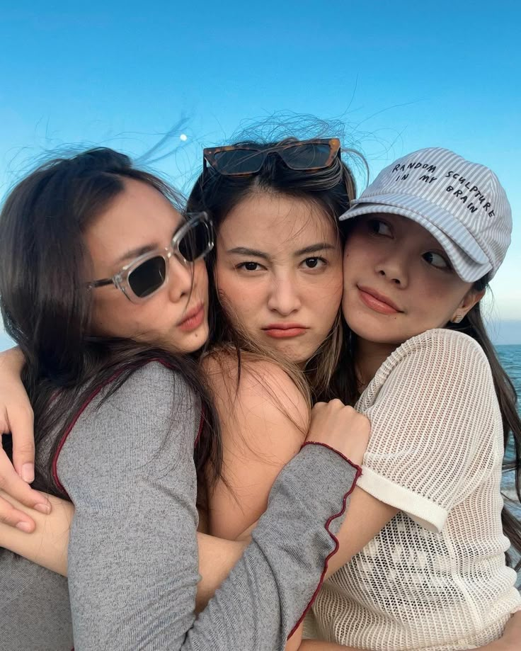 three girls hugging each other on the beach