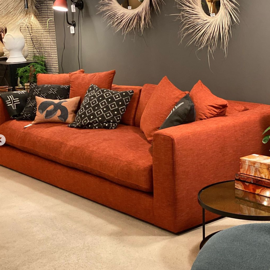 a living room with orange couches and decorative mirrors on the wall ...