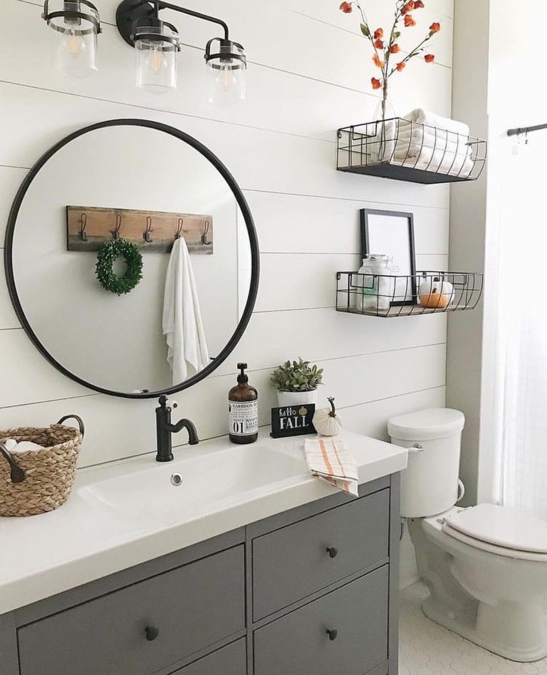 gray bathroom cabinets, farm sink, round black framed mirror, back wire