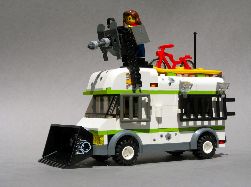 a lego bus with a man standing on top of it's roof holding a bike