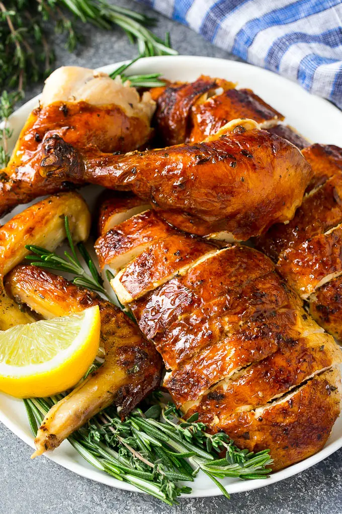 Carved roasted chicken on a serving platter with fresh herbs. | Baked ... image.