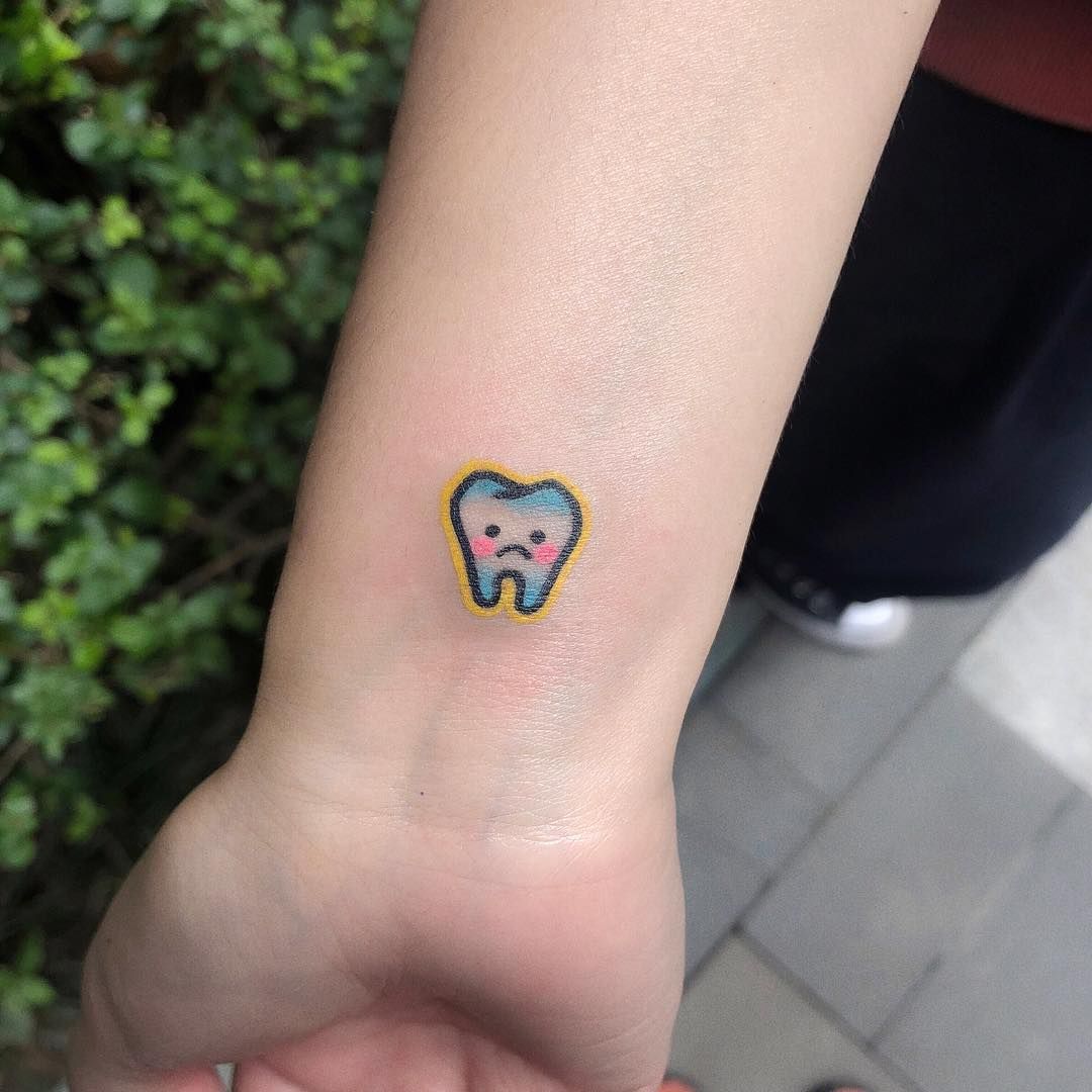 a small tooth tattoo on the wrist