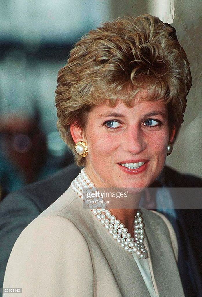 a woman in a suit and pearls smiles at the camera