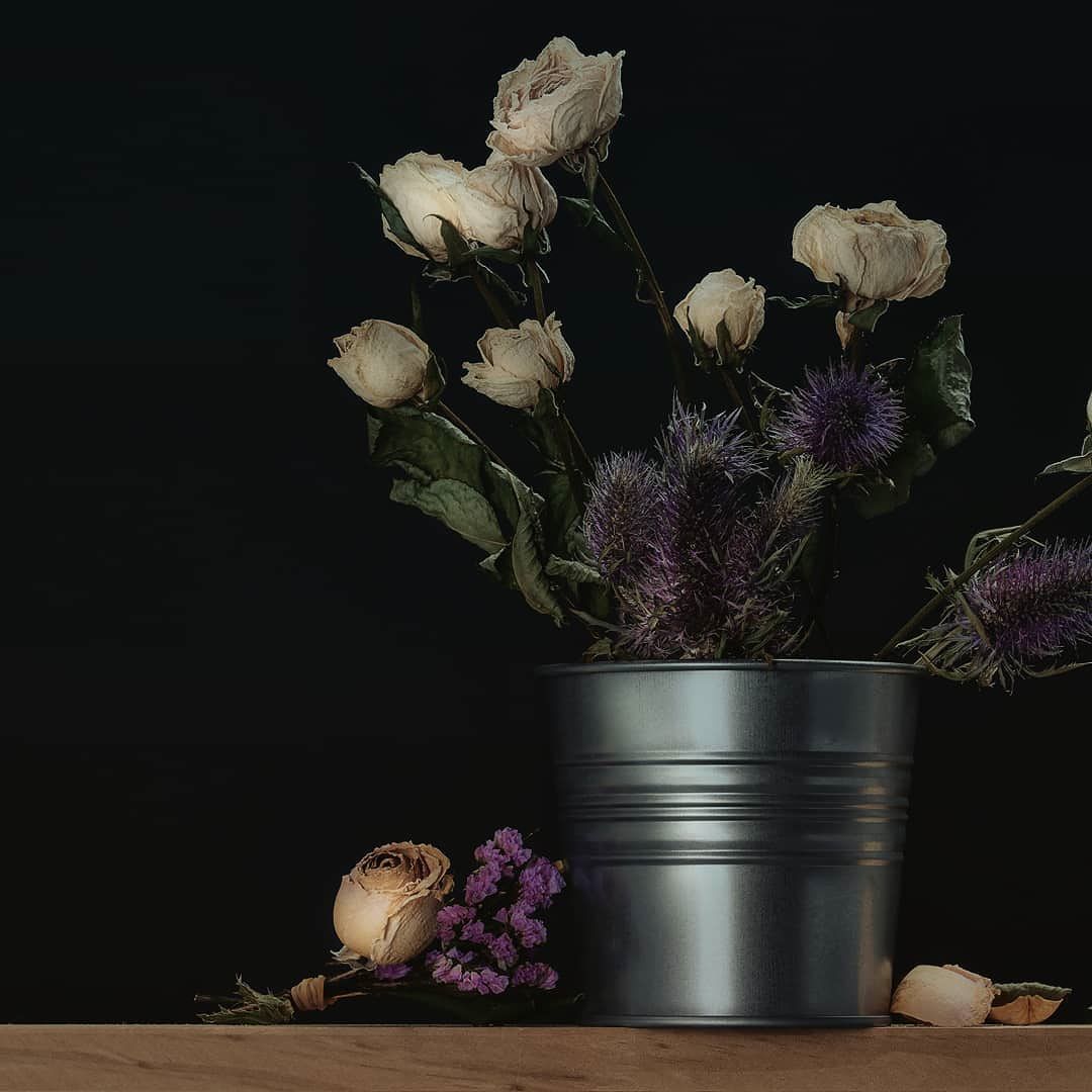 white flowers are in a metal container on a table