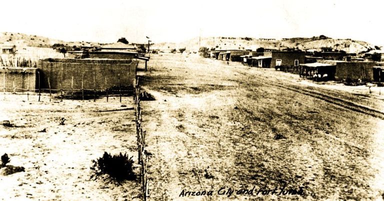 an old black and white photo of a dirt road in the middle of town with ...