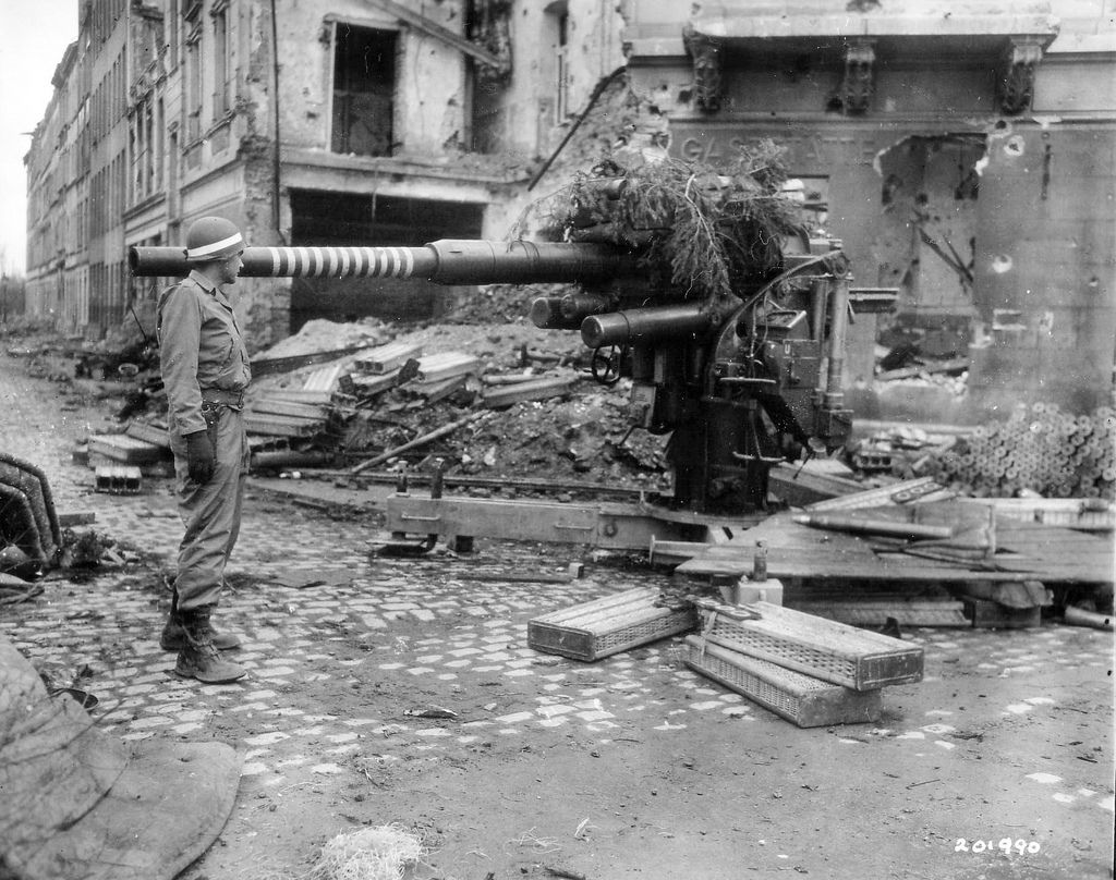 An American MP examines a German 88mm anti-aircraft FlaK 18 used as an ...