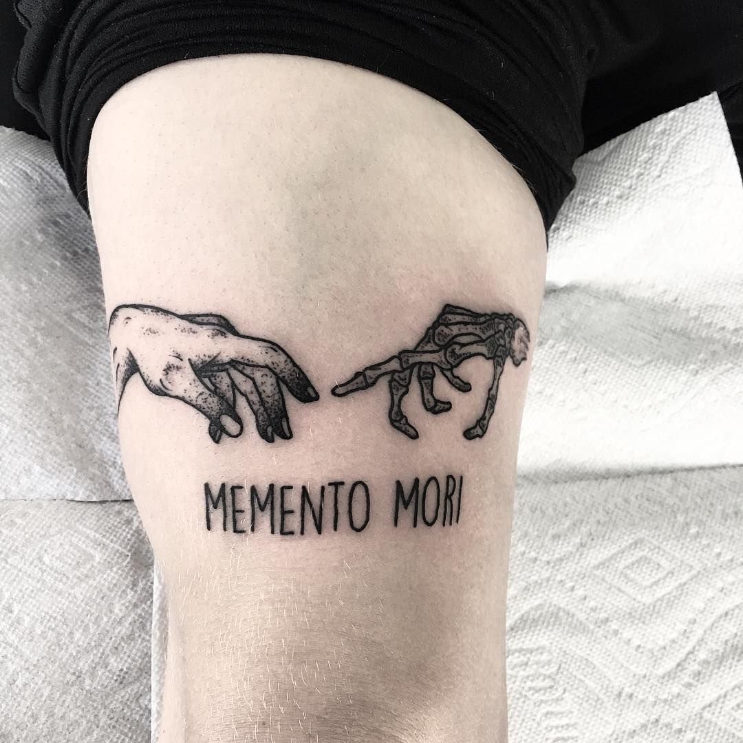 two hands touching each other with the words mementoo mori tattooed on them