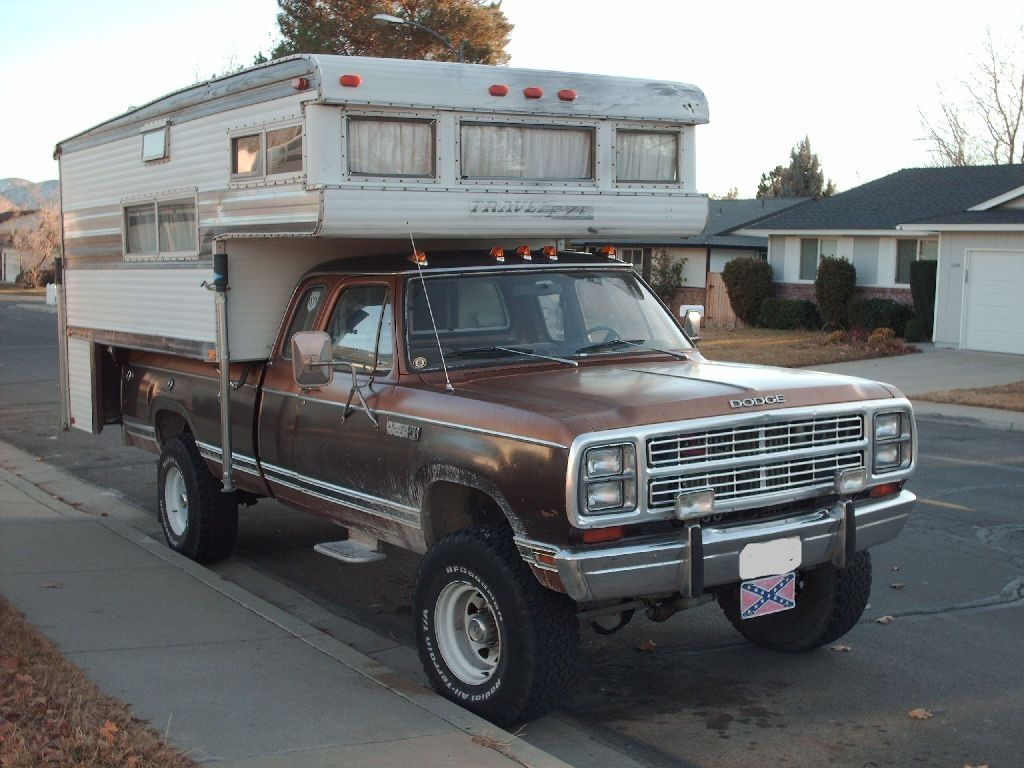 an old truck with a camper attached to it's bed parked in front of a house