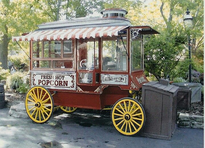 an old fashioned popcorn cart is parked on the side of the road in ...