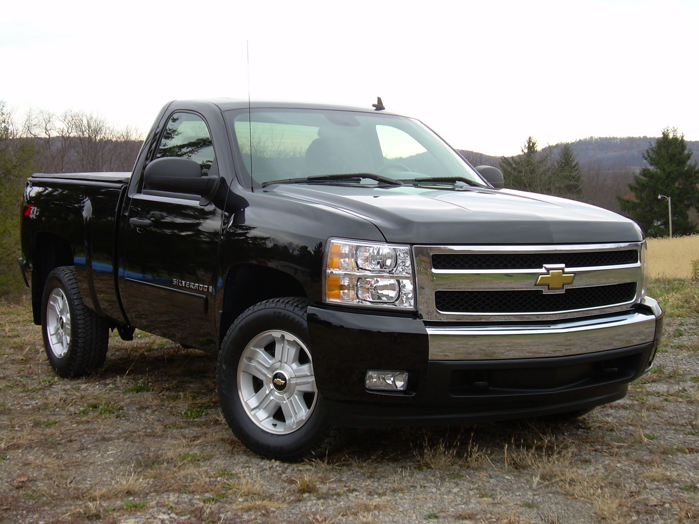 a black pickup truck parked on top of a grass covered field