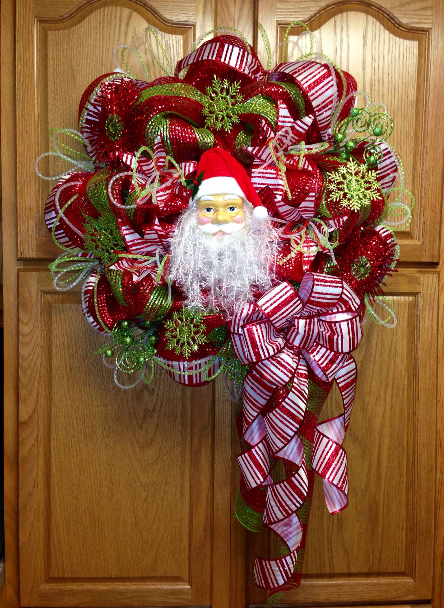 a red and green christmas wreath with a santa clause on it's front door