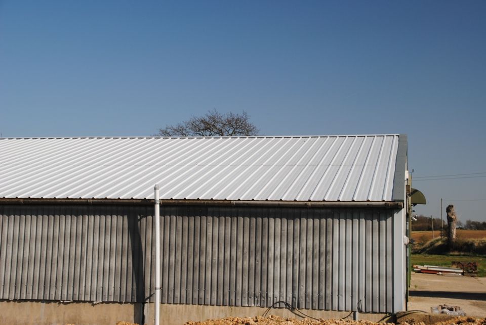 an industrial building with a metal roof and large windows on the side ...