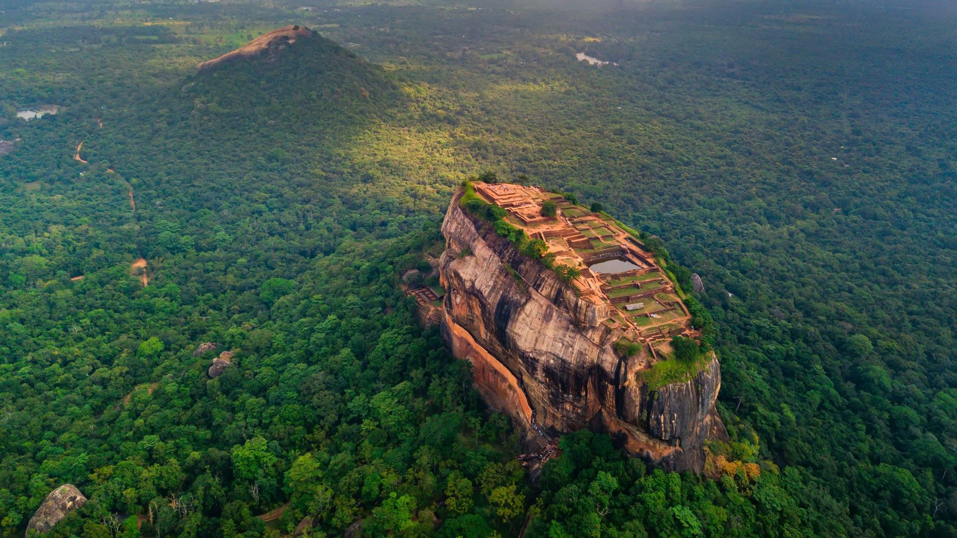 an aerial view of the top of a mountain with trees and clouds in the ...