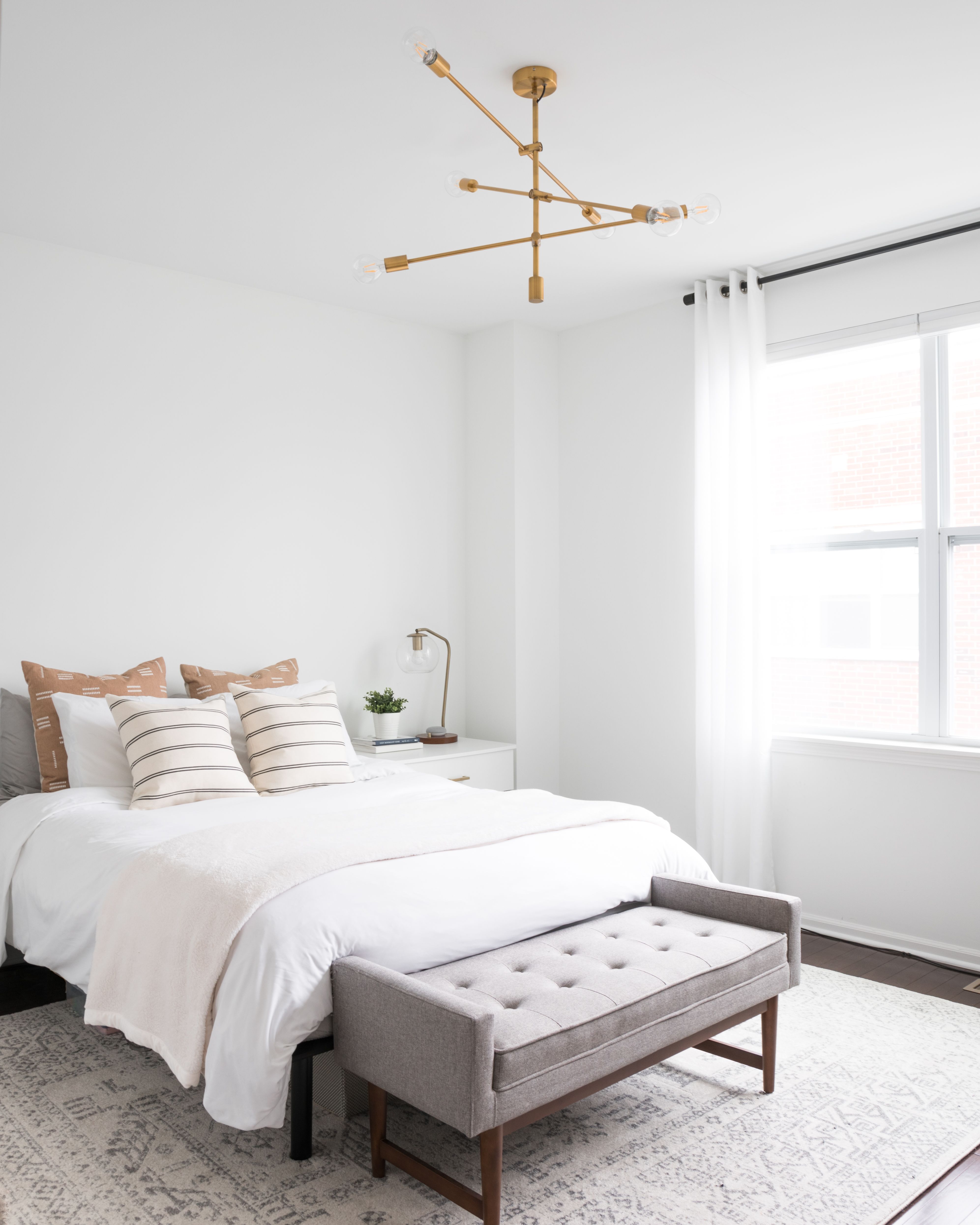 a bedroom with a bed, ottoman and window