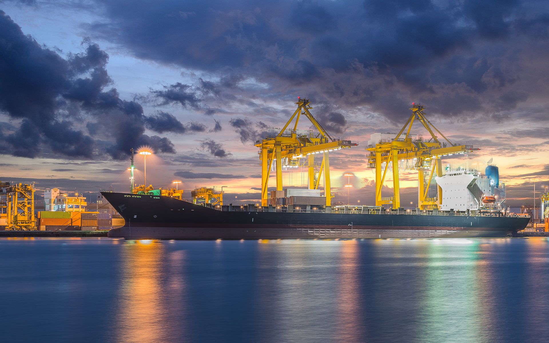 a large cargo ship in the water with some cranes on it's side at sunset