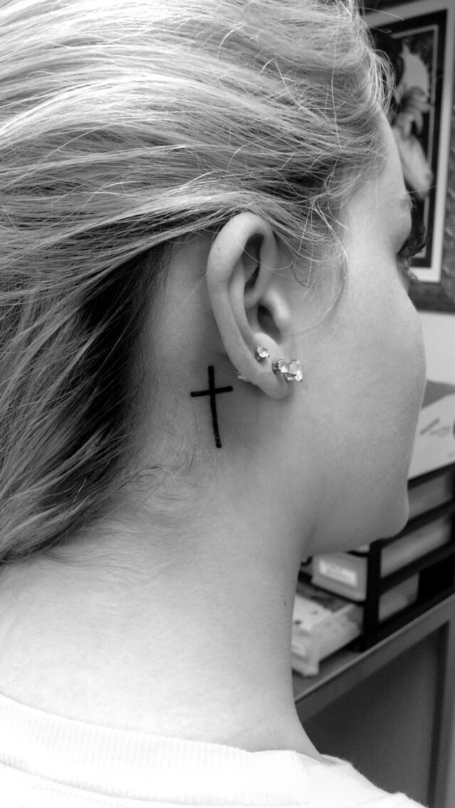 Minimalistic little cross tattooed behind the ear