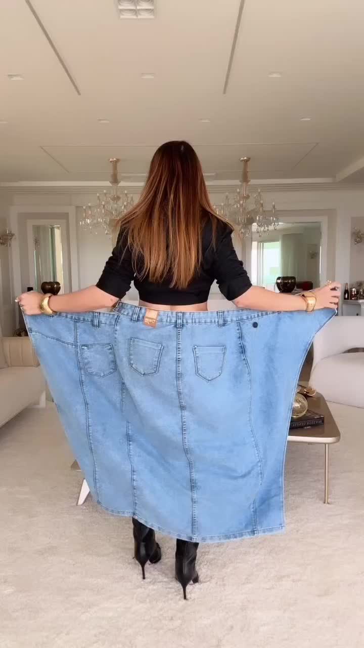 This may contain: a woman holding up a large blue jean skirt in the middle of a living room