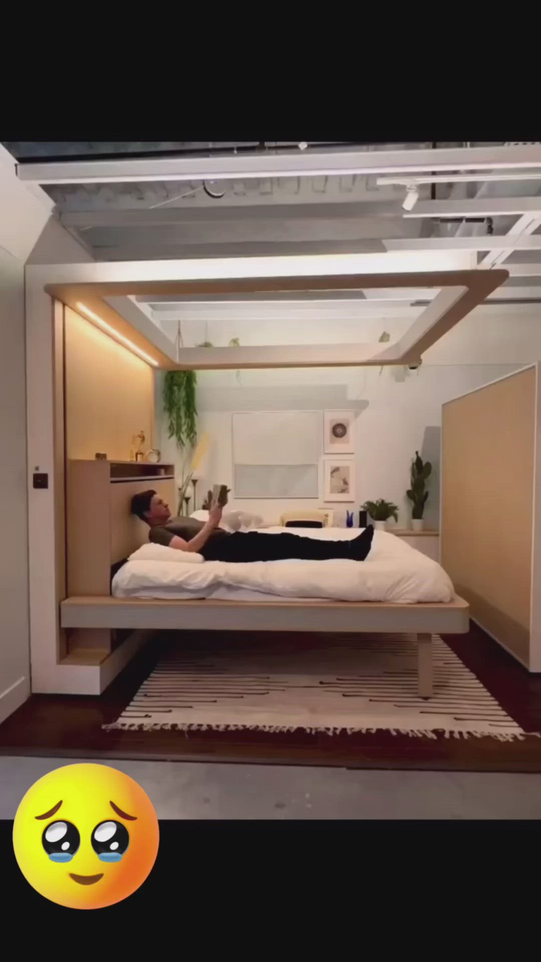 This may contain: a man laying on top of a bed in a room with white walls and wooden floors