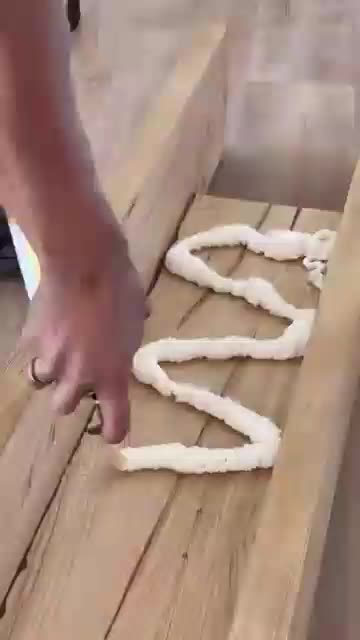 This may contain: a person is making some kind of snake out of wood