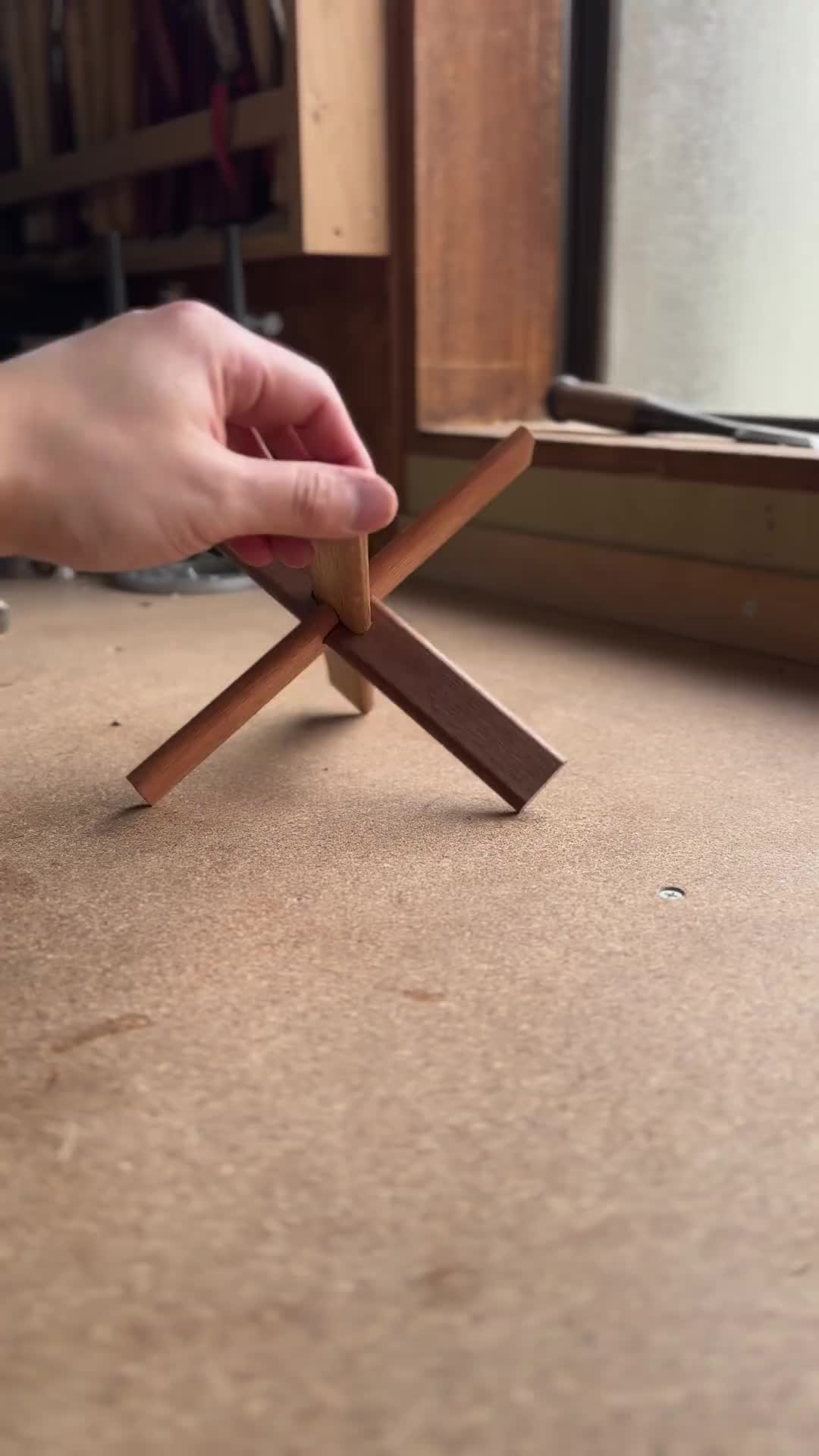 This may contain: a person holding a piece of wood on top of a wooden floor next to a window