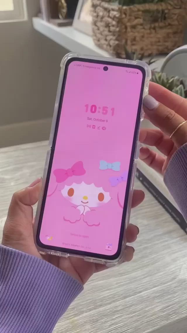 This may contain: a person holding an iphone in their hand with hello kitty stickers on the screen