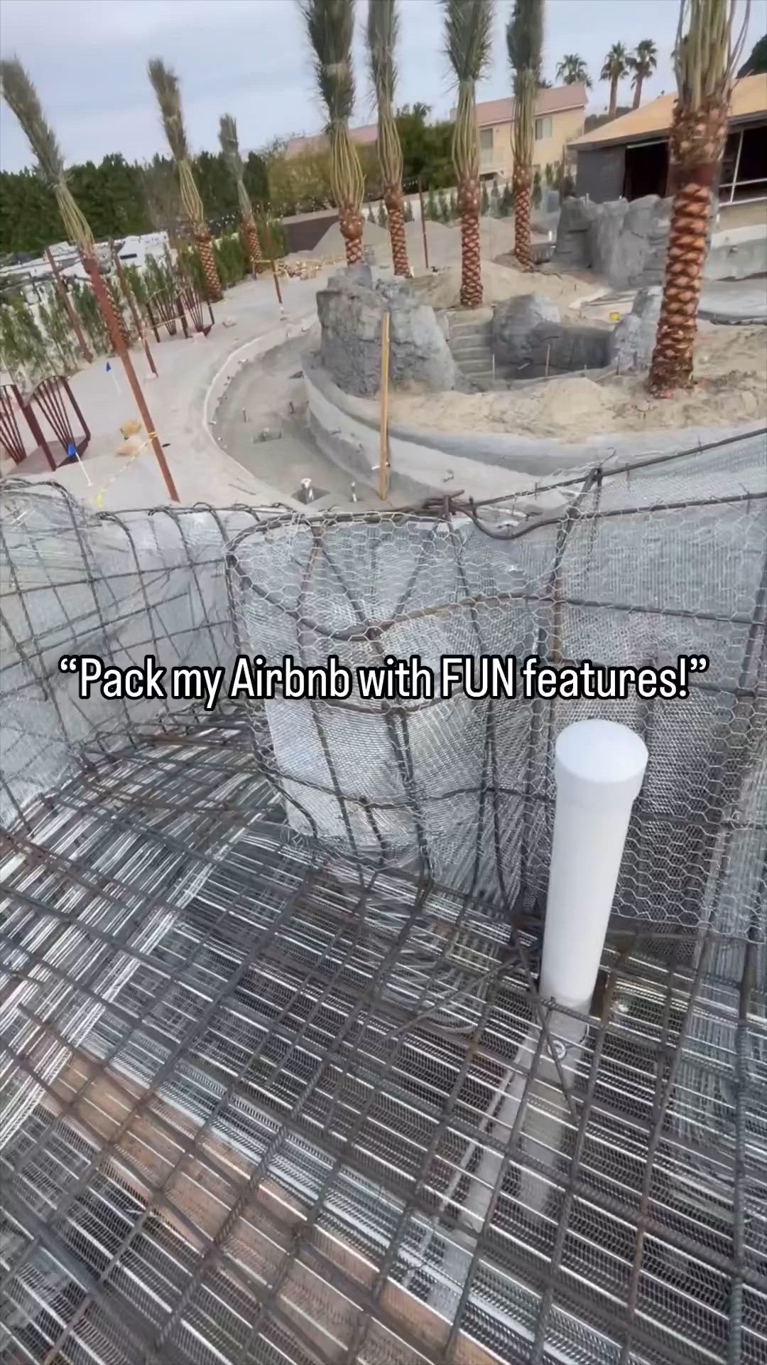 This may contain: an artificial pool surrounded by palm trees and rocks