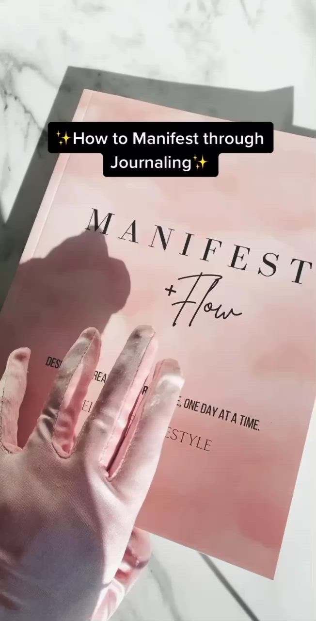 This may contain: a person is writing in a journal with the title how to manifit through journaling