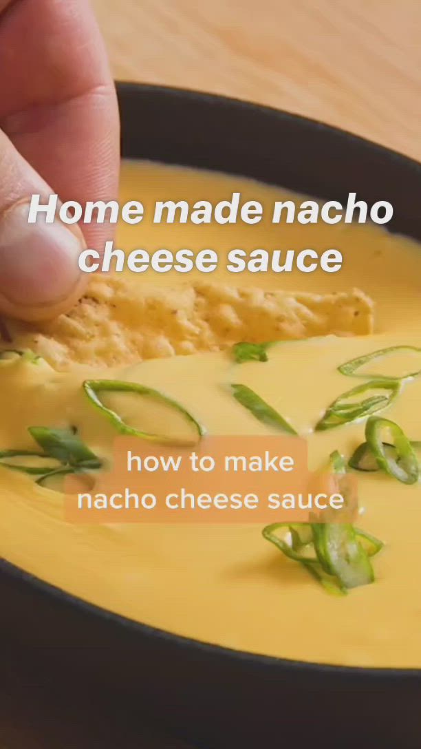 This may contain: a hand dipping cheese sauce into a bowl with green peppers on the side and text that reads, home made nacho cheese sauce how to make nacho cheese sauce