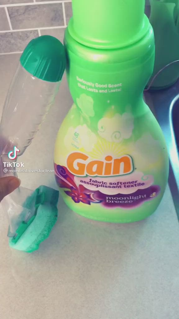 This may contain: a hand is holding a plastic cup with blue and green stuff in it next to a bottle