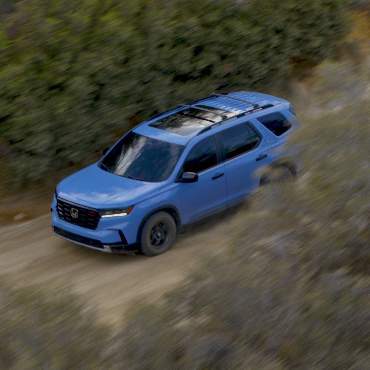 This may contain: a blue suv driving down a dirt road