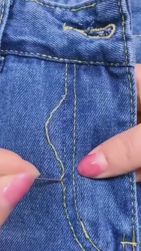 This may contain: someone is stitching on the side of their jean pants with pink nail polishes