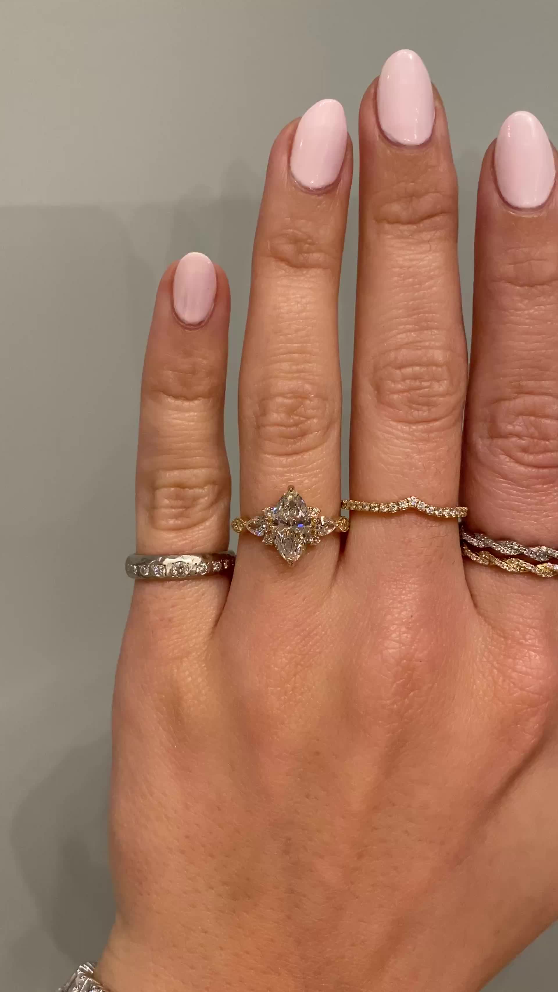 This may contain: a woman's hand with three different rings on her fingers and one ring in the middle