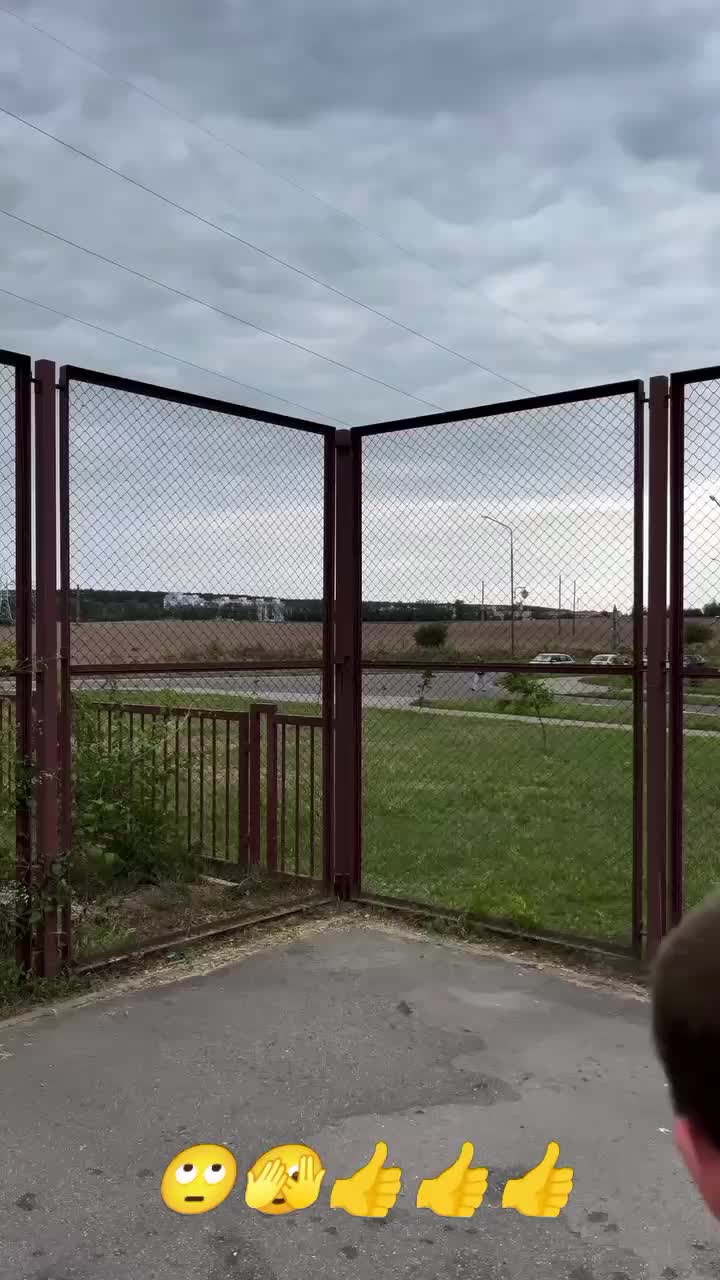 This may contain: a young boy is playing with some yellow smiley faces on the ground in front of a fence