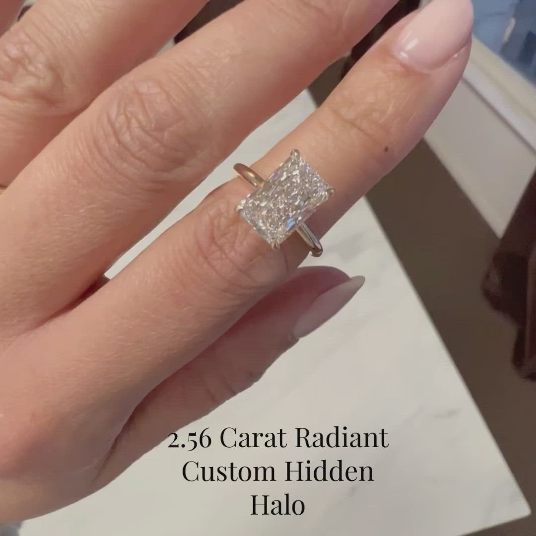 This contains: Video of 2.56 Radiant cut lab grown diamond sat in a yellow gold solitaire with a Hidden Halo shown on hand.