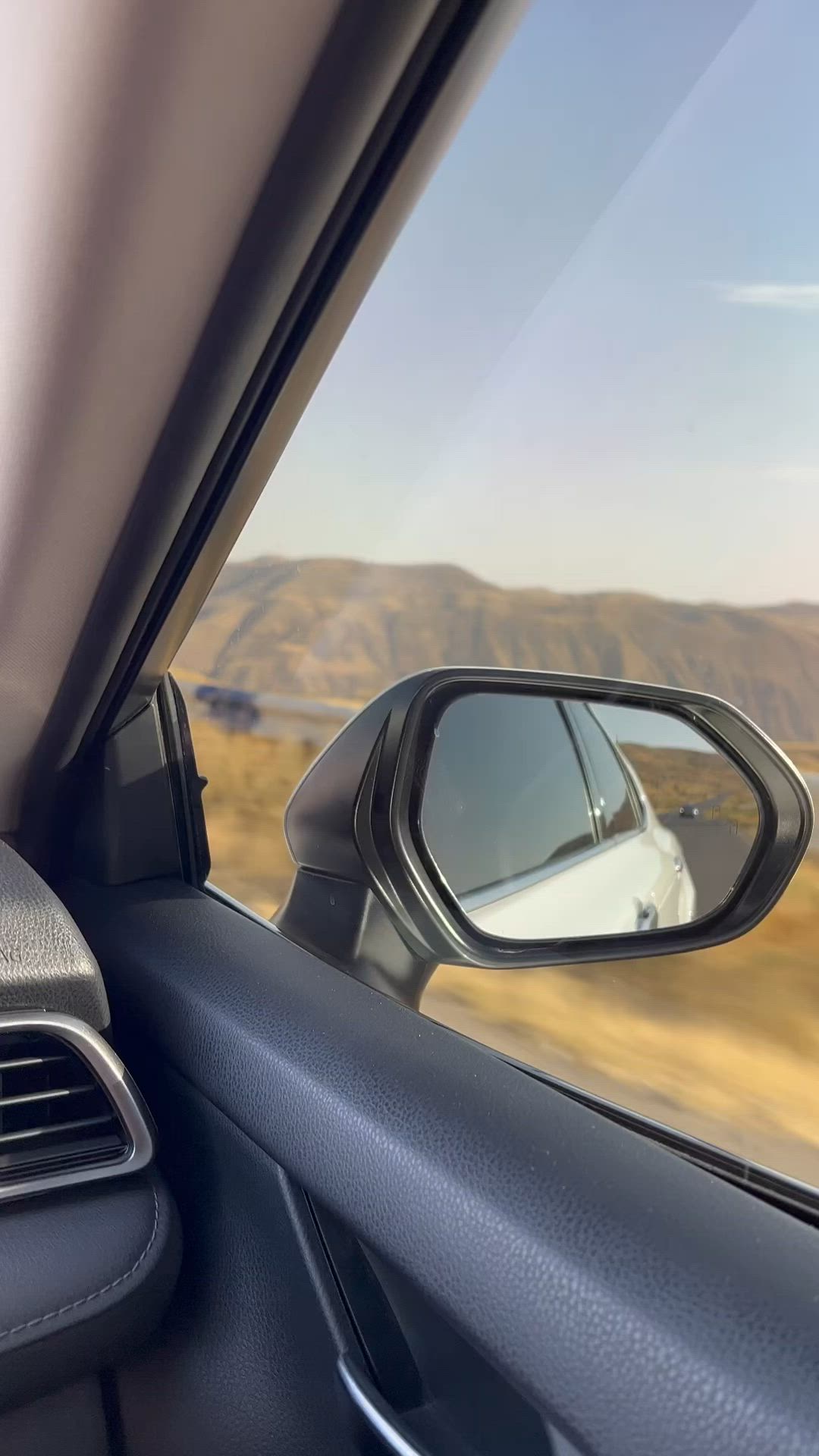 This may contain: the side view mirror of a car driving down a road