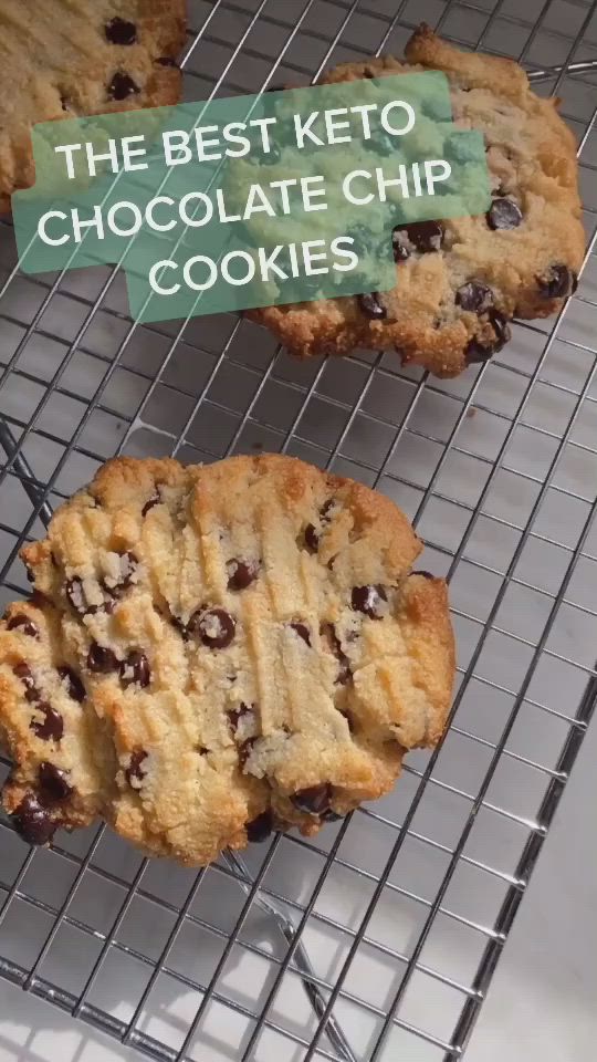 This may contain: the best keto chocolate chip cookies are cooling on a wire rack with a sign that reads, the best keto chocolate chip cookies