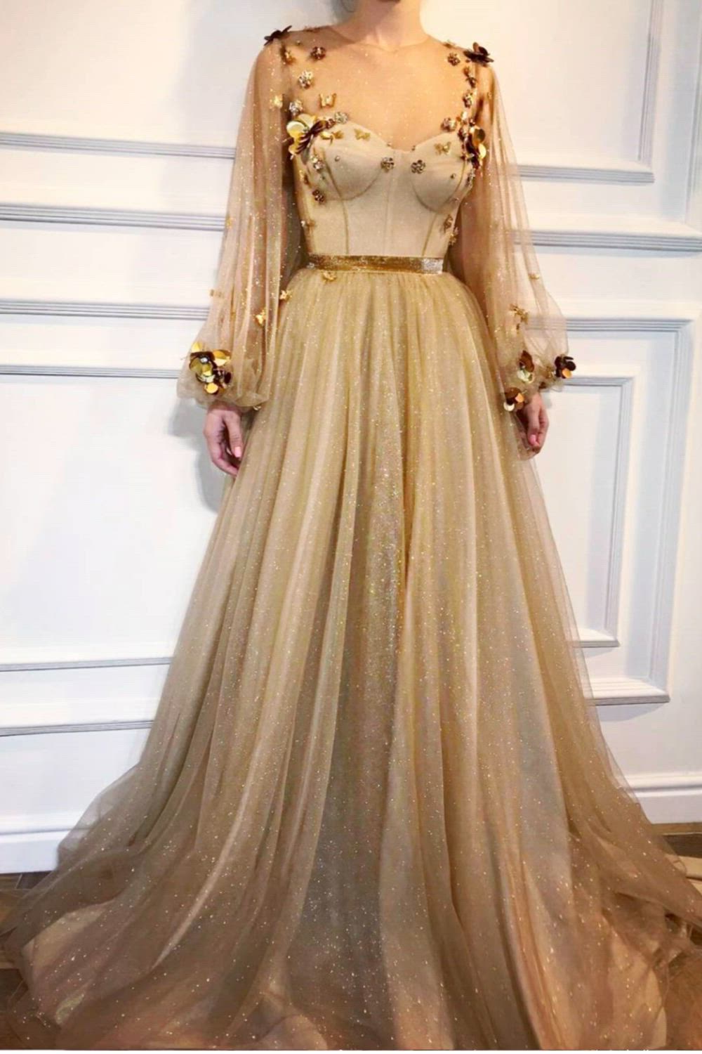 This stunning Royal gold dress is perfect for any evening party or special event! The dress is made with a beautiful Sparkling tulle fabric and is adorned with Handmade embroidered fields flowers and butterflies. The dress also features a shiny belt detail and a Ball gown style with long-sleeves.