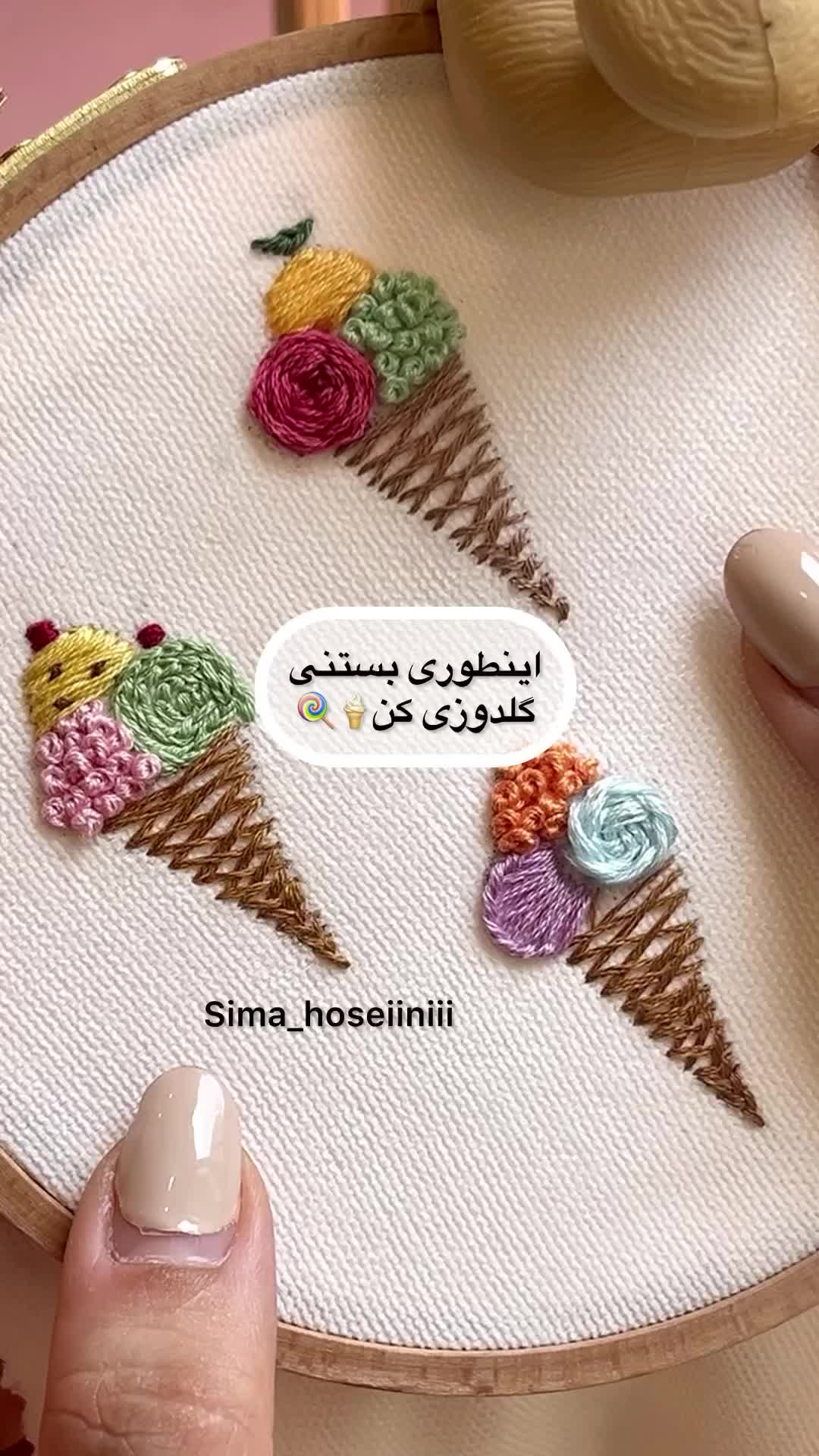 This may contain: a woman's hand is holding a cross stitch project with flowers and ice cream cones on it