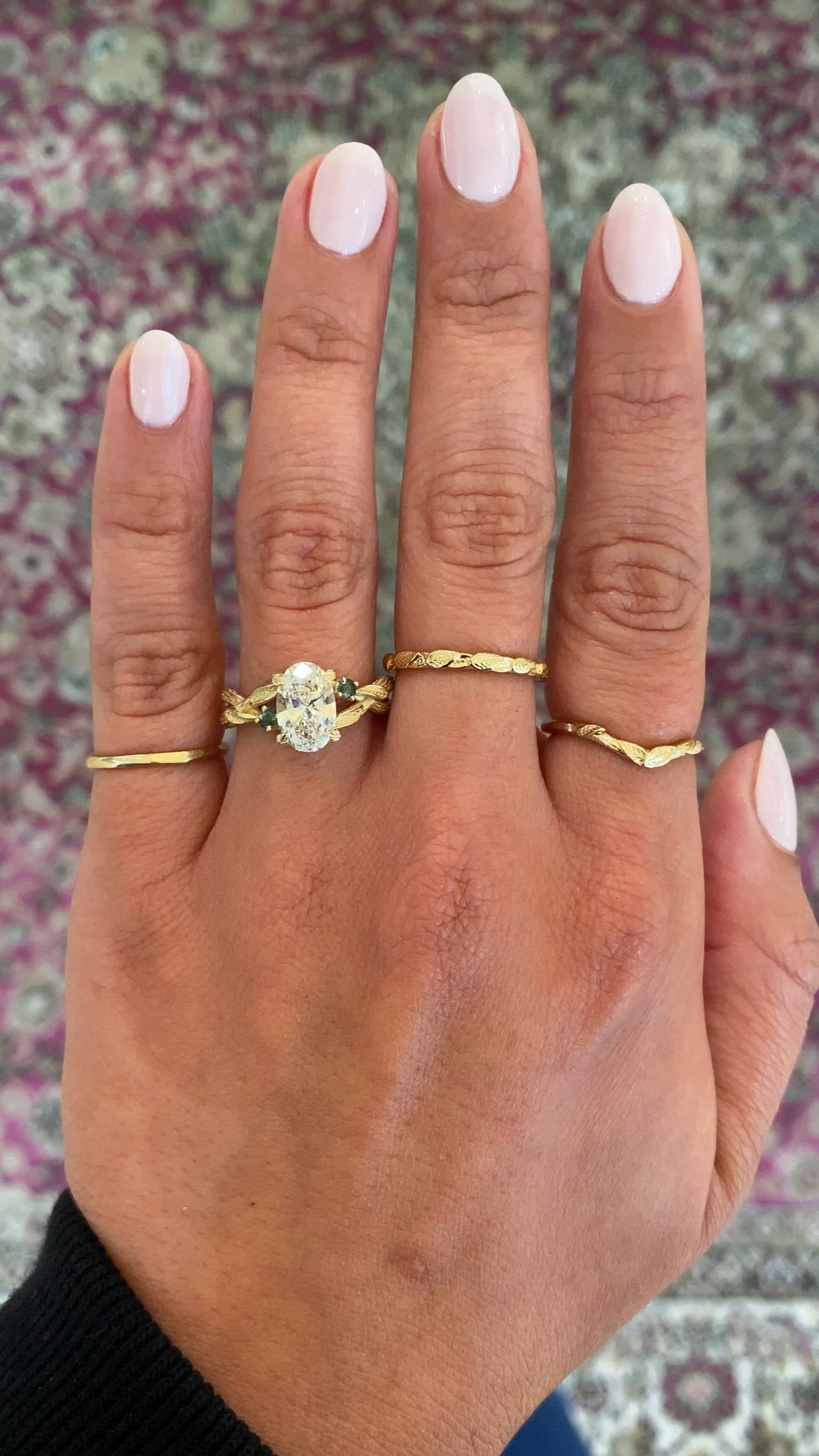 This may contain: a woman's hand wearing a gold ring with an oval diamond on the middle