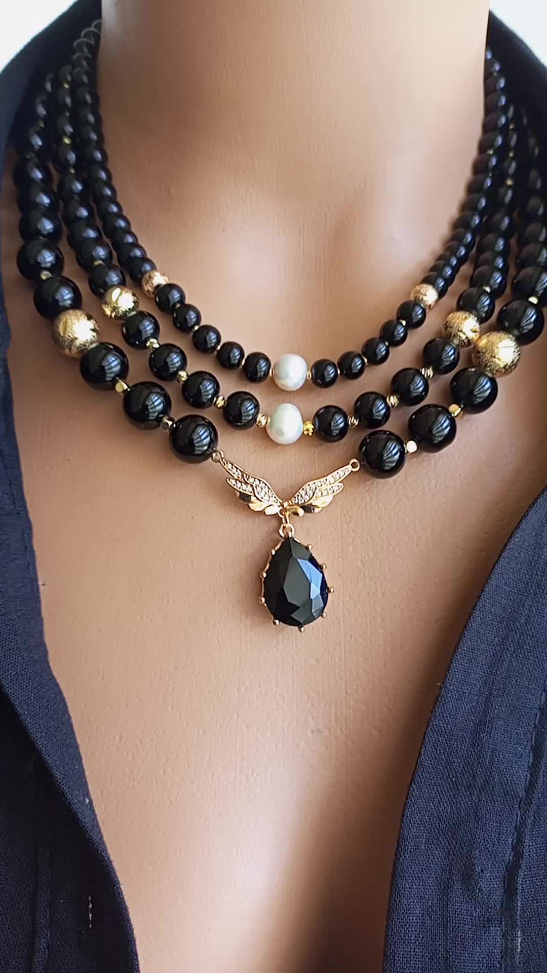 A true statement piece that exudes elegance and sophistication, our elegant Onyx Multi-Strand Black Beaded Necklace consists of numerous sparkling onyx beads and zircon bird wing pendants, carefully handcrafted and meticulously assembled to create a stunning visual effect. Shiny black onyx beads, known for their grounding and protective properties, add a mystical touch to this elegant boho accessory.