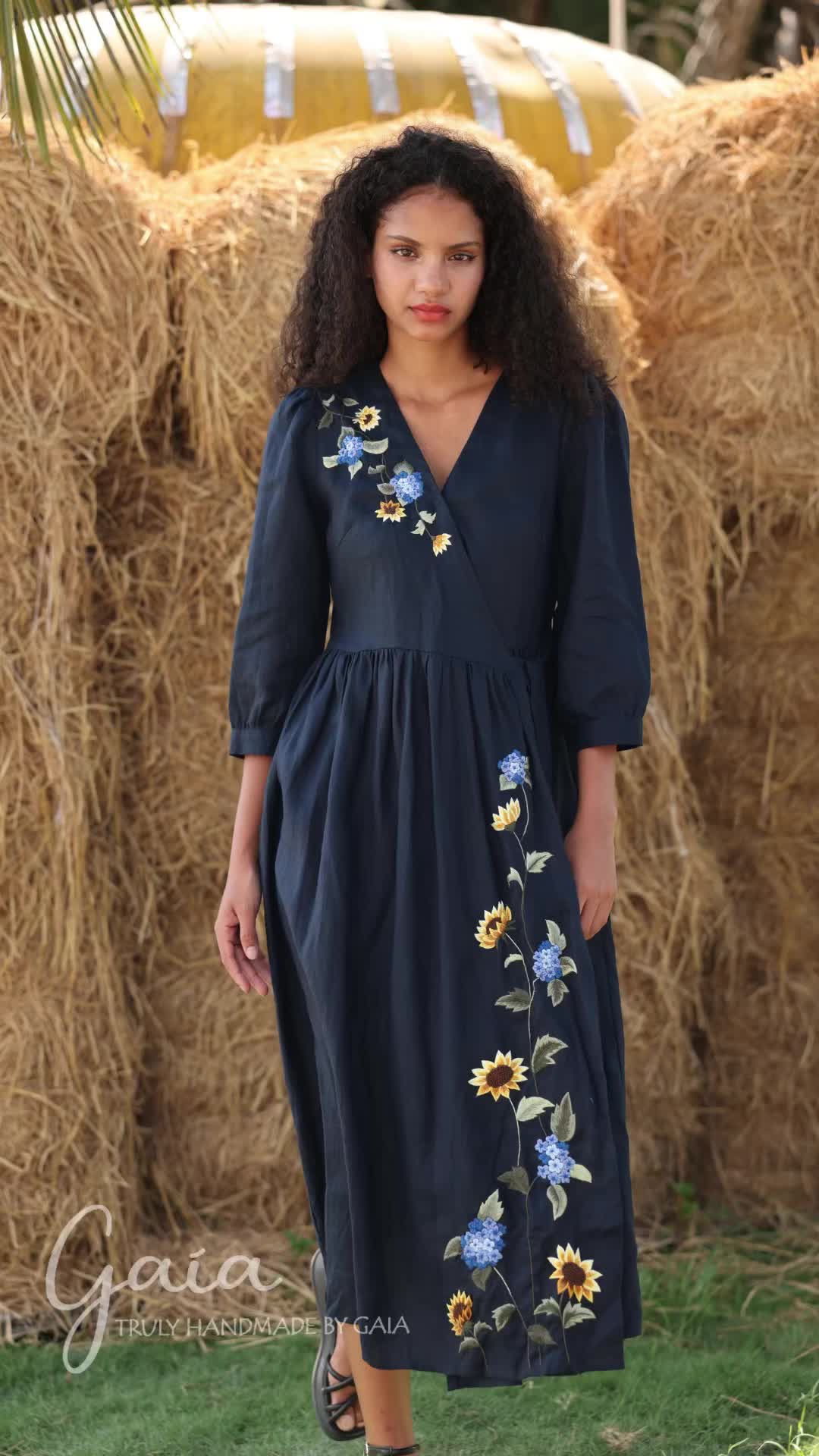 This may contain: a woman standing in front of hay bales wearing a dress with sunflowers on it