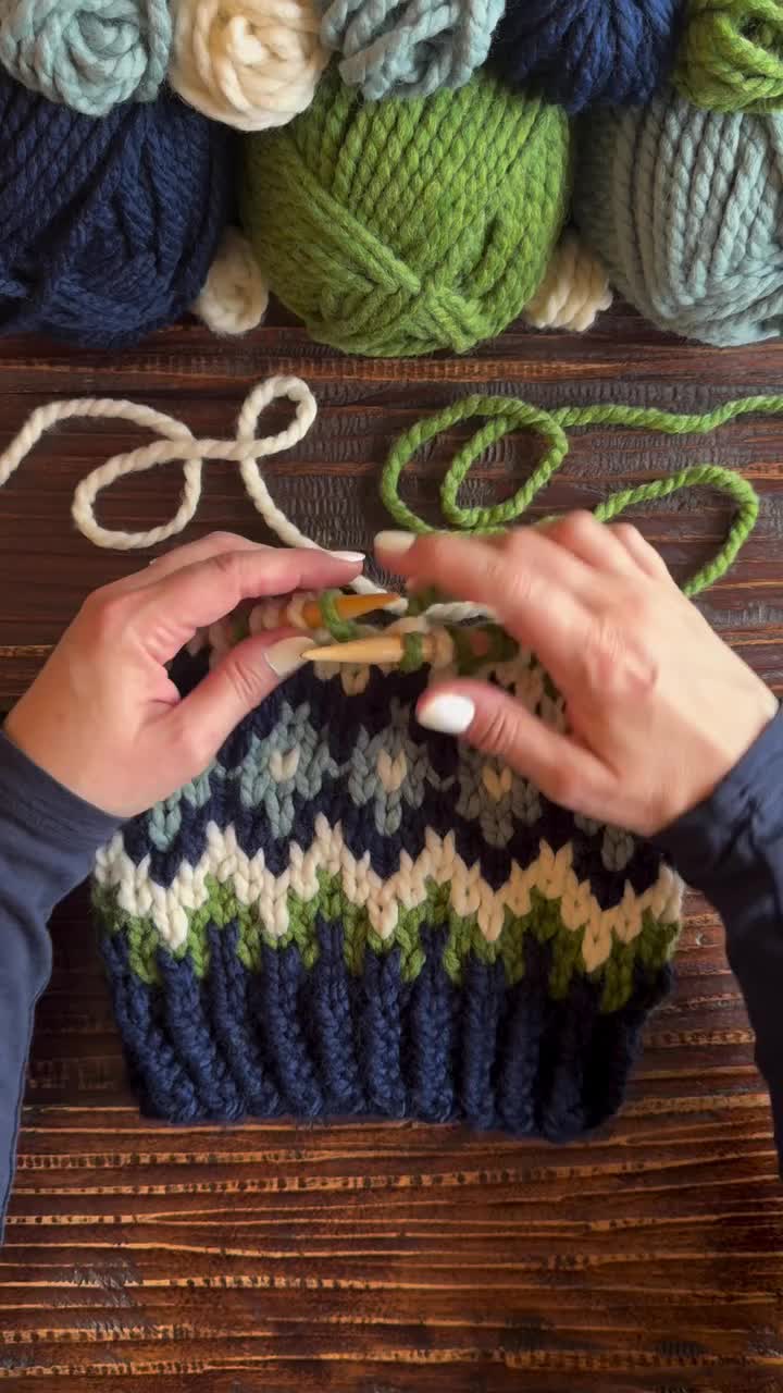 This may contain: someone is knitting something on the table with yarn and crochet hooks in front of them