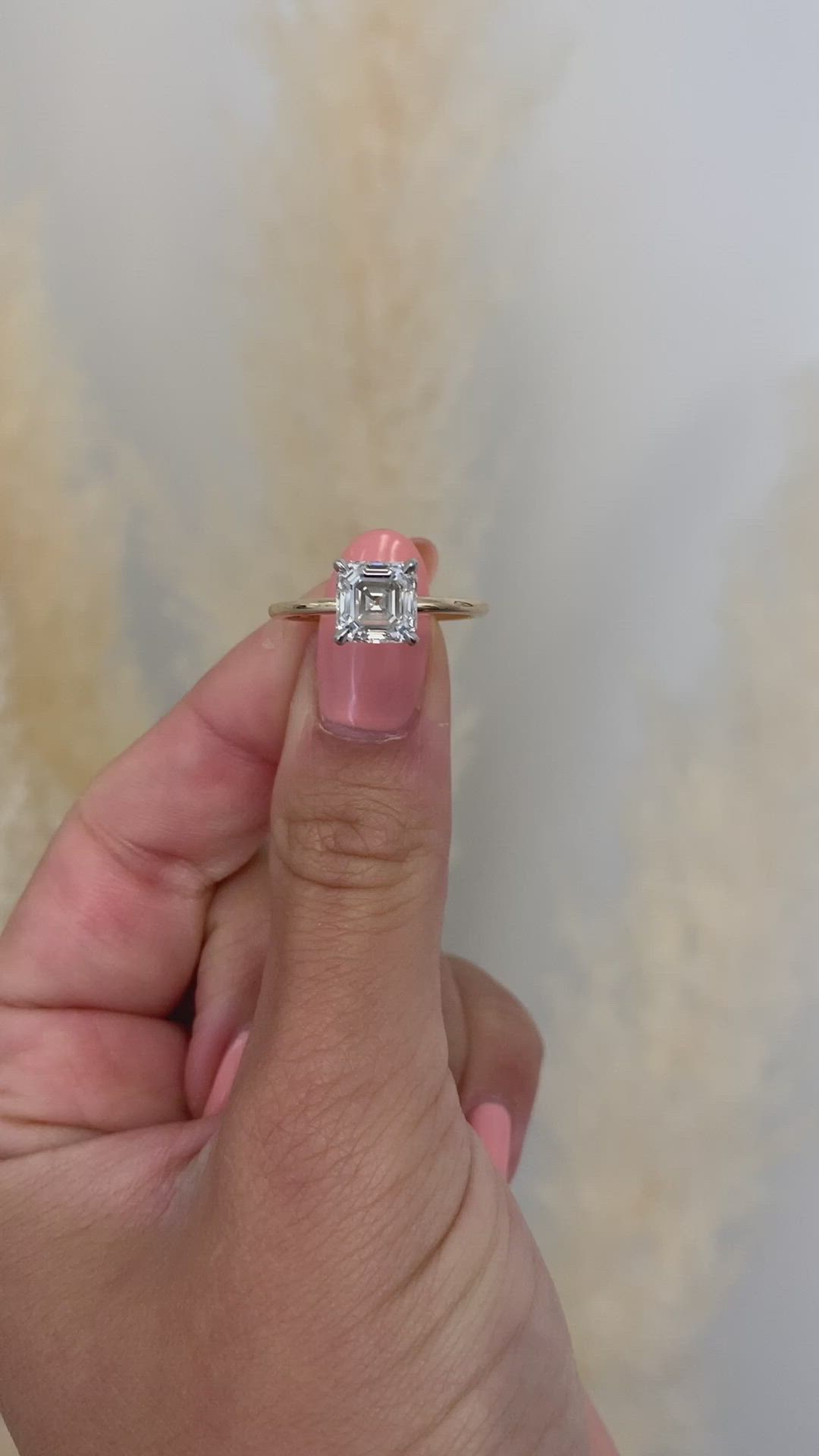 This may contain: a person holding a ring with a diamond in it's middle, on top of their finger