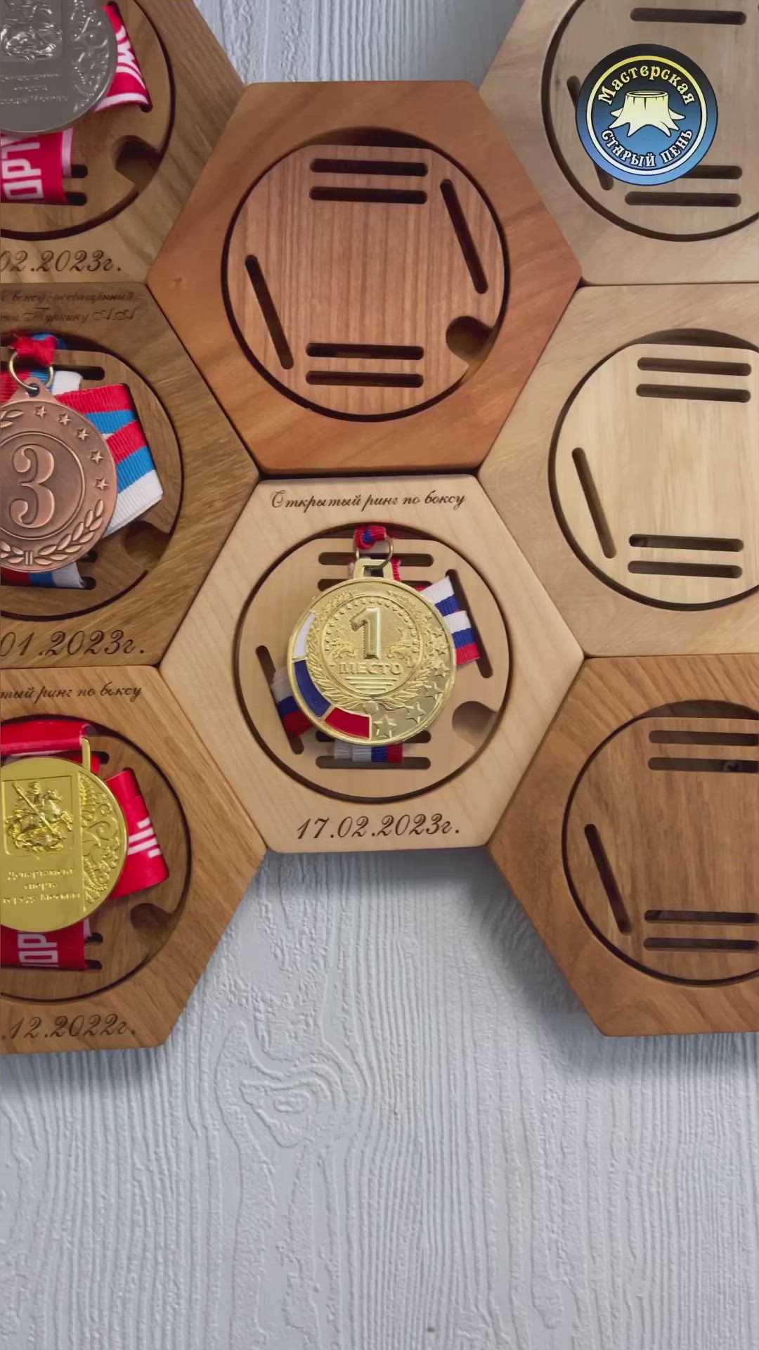 This may contain: a person holding up a medal in front of some wooden hexagons with medals on them