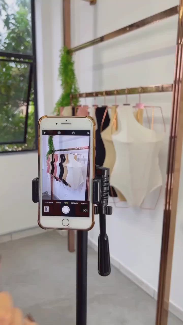 This may contain: a cell phone is being held up in front of a mirror with clothes hanging on it