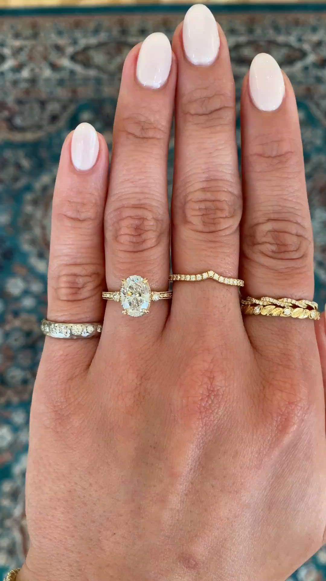 This may contain: a woman's hand with three different rings on her fingers and one ring in the middle