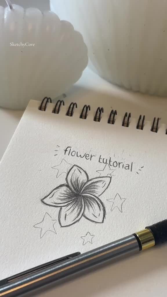 This may contain: a notepad with a flower on it next to a pen