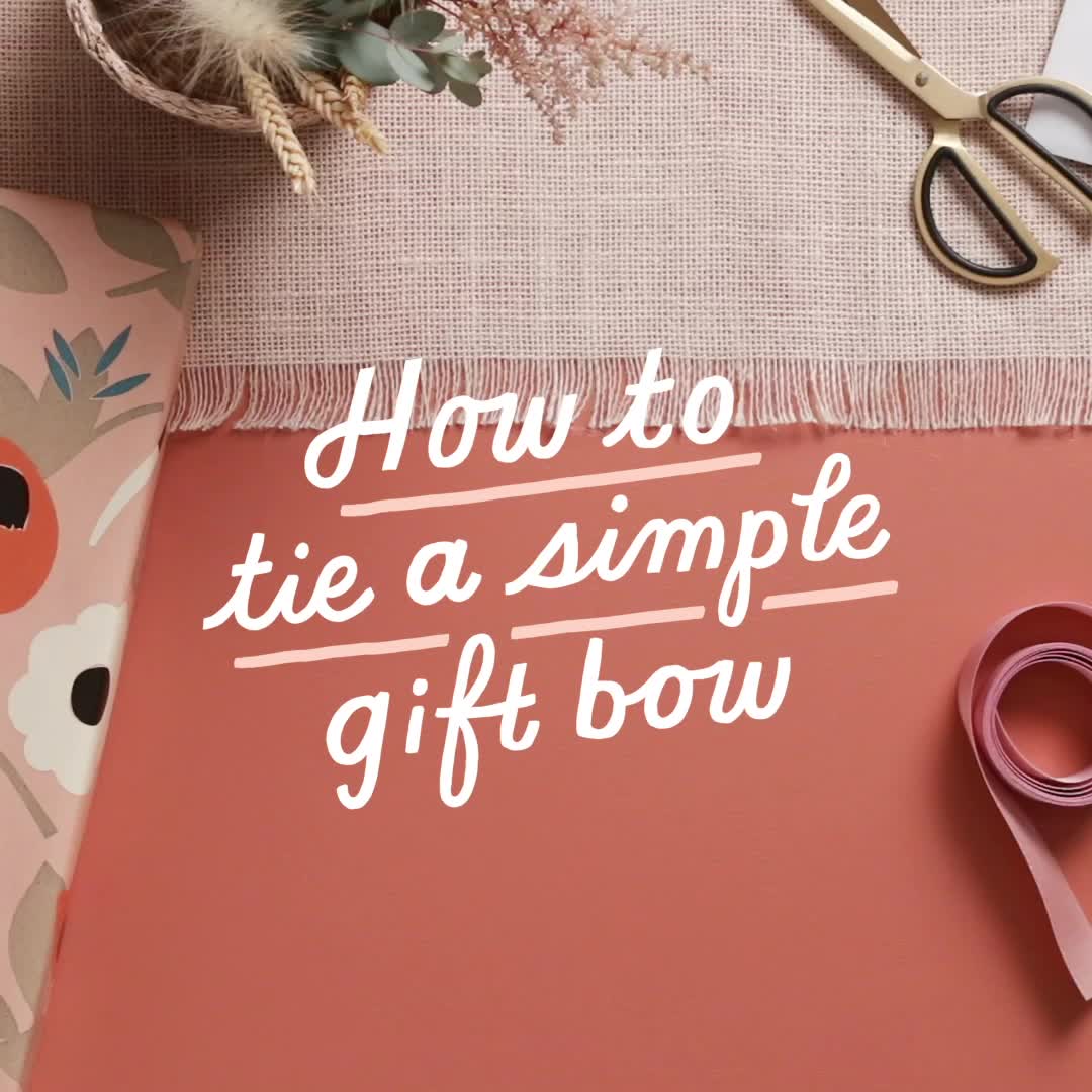 This may contain: a pink gift box with scissors on it and the words how to tie a simple gift bow