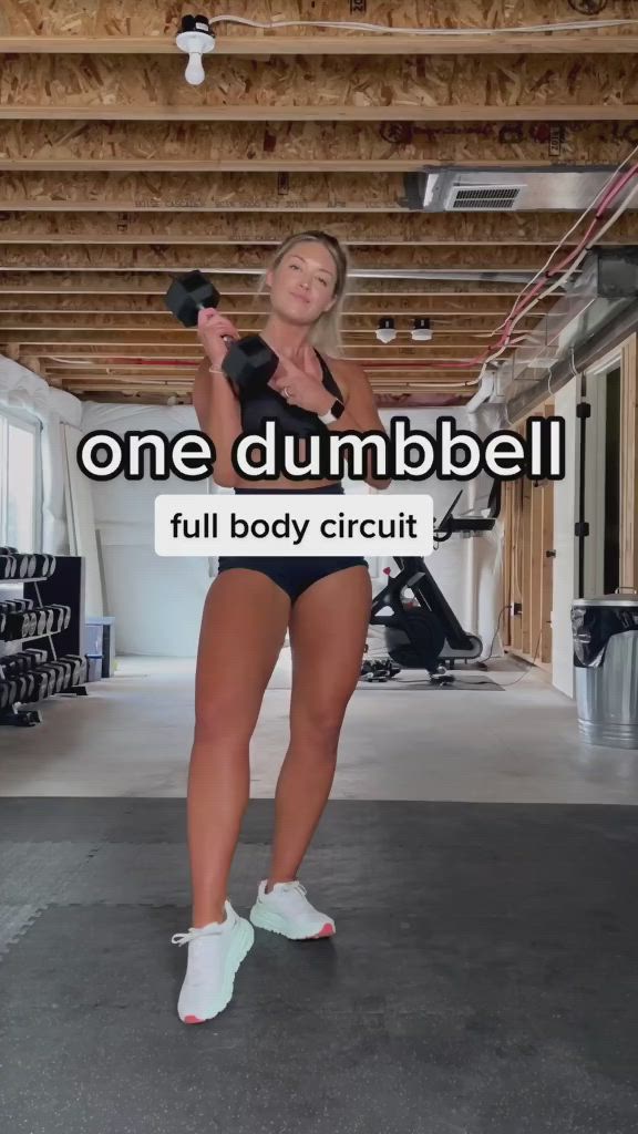 This may contain: a woman in a black top and blue shorts is holding a dumbbell with the words, one dumbbell full body circuit